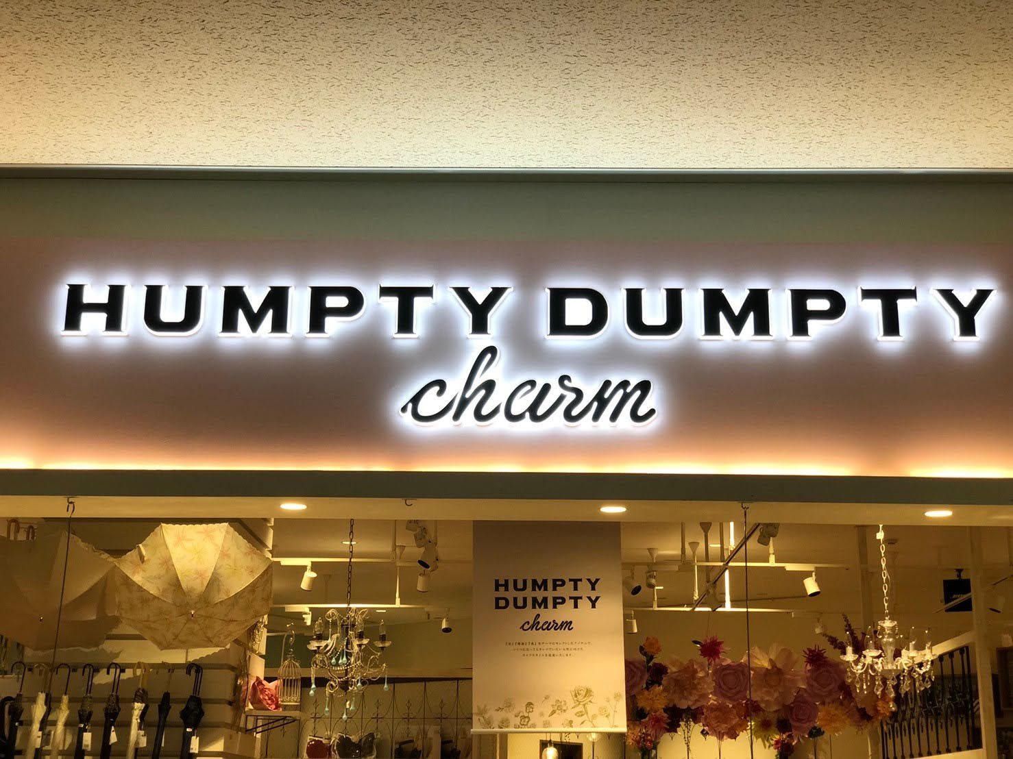 商業施設内の店構え根元発光サイン「HUMPTY DUMPTY charm」(白色発光で明るい壁面に映える)