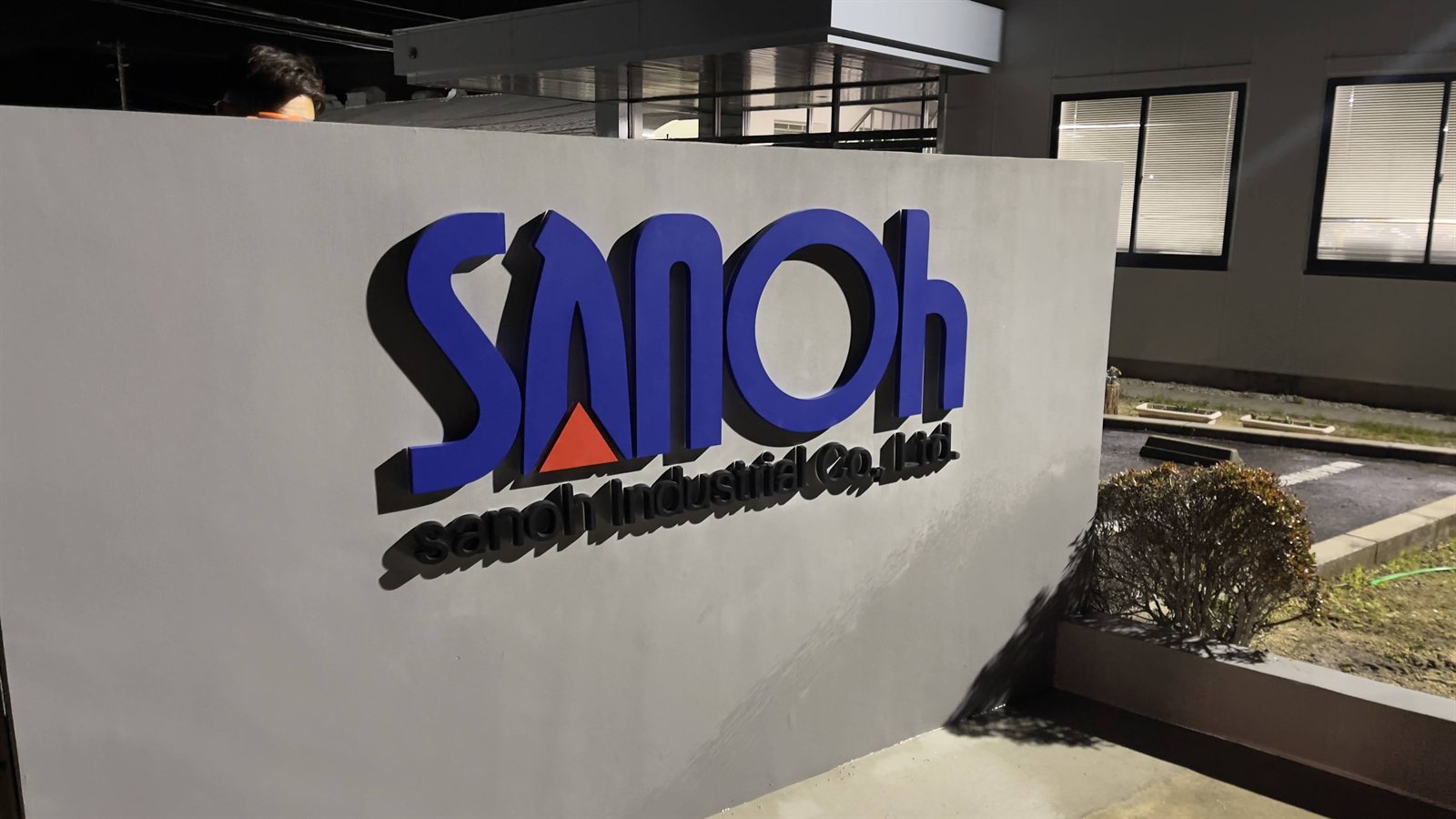 屋外設置の根元発光サイン「Sanoh Industrial」(防水仕様・青ロゴ・企業エントランス)