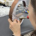チャンネル文字の内部にLEDをはんだ付けで組み込む職人の手元（製作中）