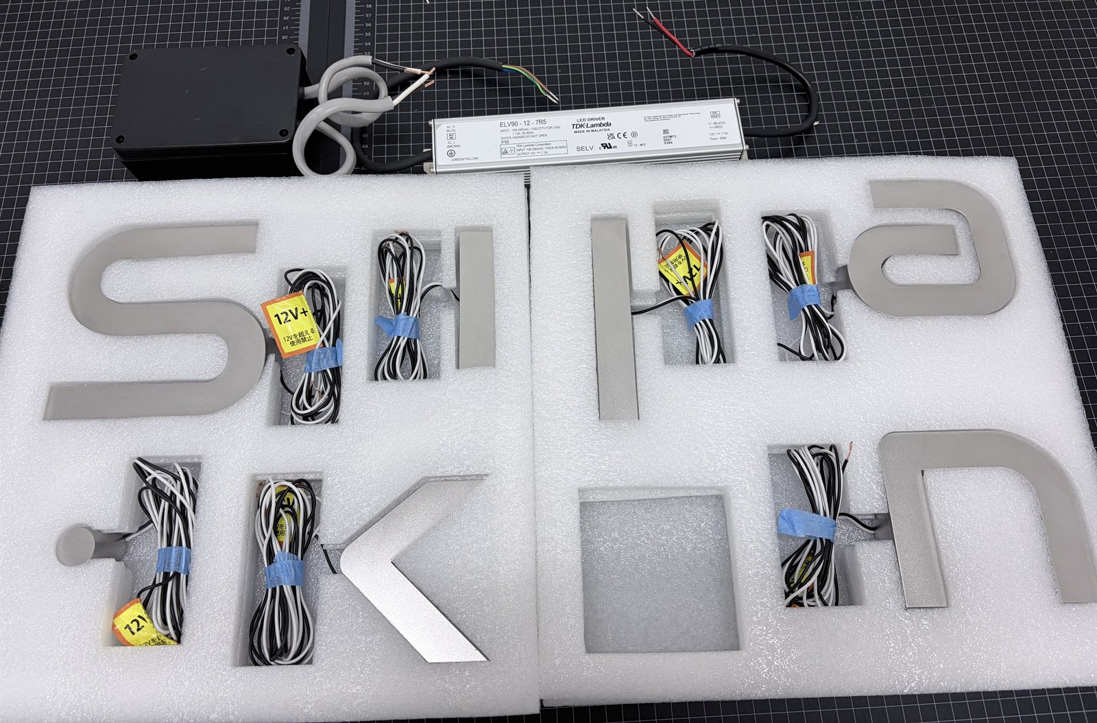 出荷前の梱包 緩衝材に1点ずつ収めたLEDチャンネル文字と12Vタグ付きの配線・LEDドライバー
