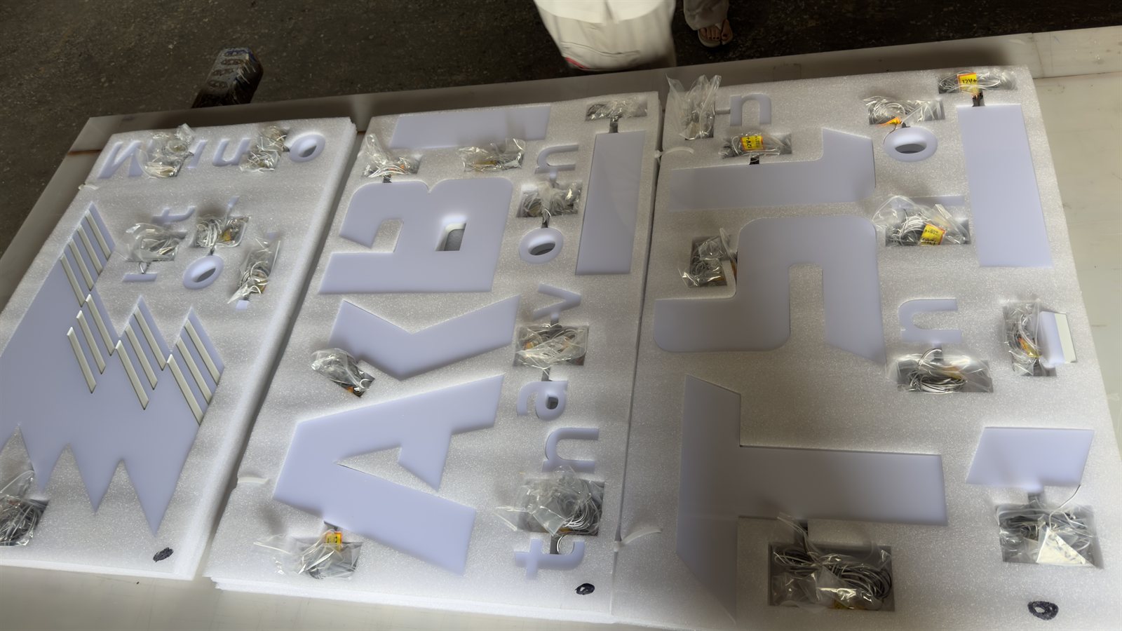 出荷前検品でアクリルパーツと取付金具を並べたLEDチャンネル文字